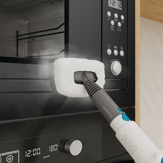 BLACK+DECKER BHSMP2008 steam mop cleaning a black oven door with microfiber pad, close-up.