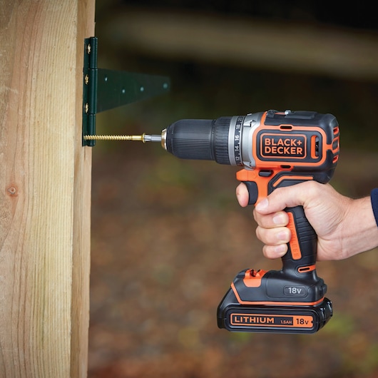 BLACKDECKER BL186K cordless drill driving screw into wooden post, close-up side angle outdoors.