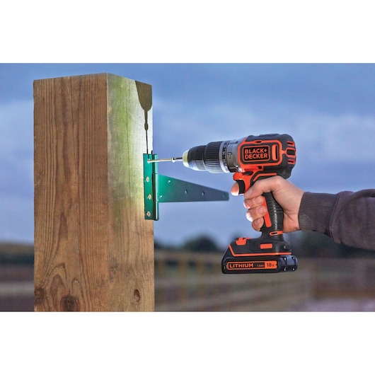 BLACKDECKER BL188K cordless drill driving screw into metal bracket on wooden post outdoors.