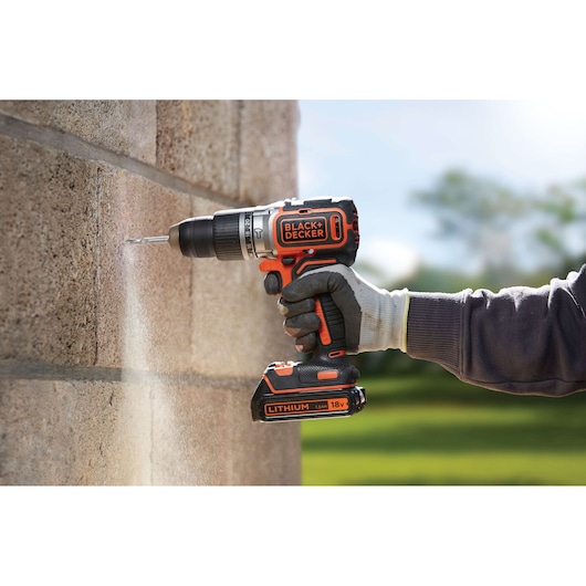 BLACKDECKER BL188K cordless drill being used on a brick wall, close-up with gloved hand outdoors.