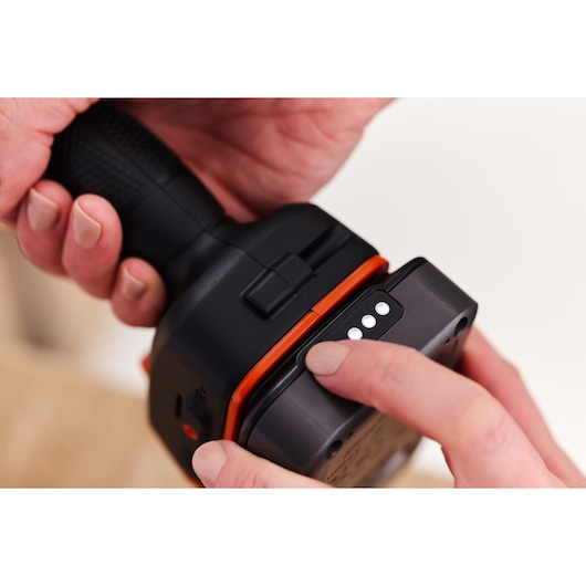 Close-up photo of BLACKDECKER BLD683D1 tool handle with hand pressing battery indicator button, white background.