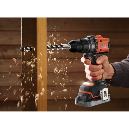 BLACK+DECKER cordless drill BLD683XN in use drilling through wood with wood shavings flying, close-up side view.