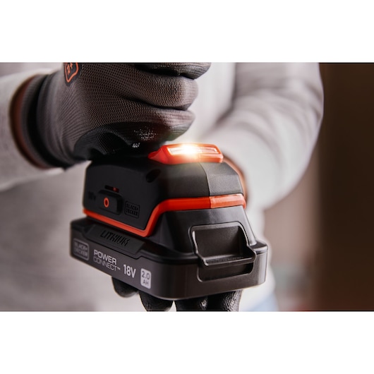 Photo of BLACK+DECKER BLD683XN 18V lithium power tool battery with LED indicator, held by a gloved hand.