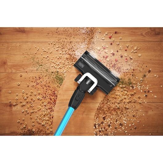 BLACKDECKER BSV520BRB cordless vacuum cleaning cereal and debris on wooden floor, top angle.