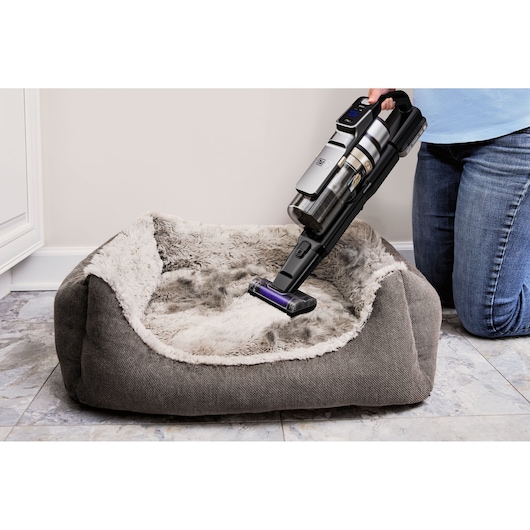 BLACKDECKER BSV525BLP cordless vacuum cleaning a gray pet bed, close-up angle.