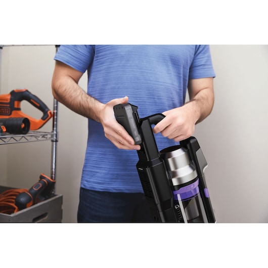 BLACKDECKER BSV525BRP cordless vacuum cleaner battery being inserted by person wearing blue shirt, indoor setting.