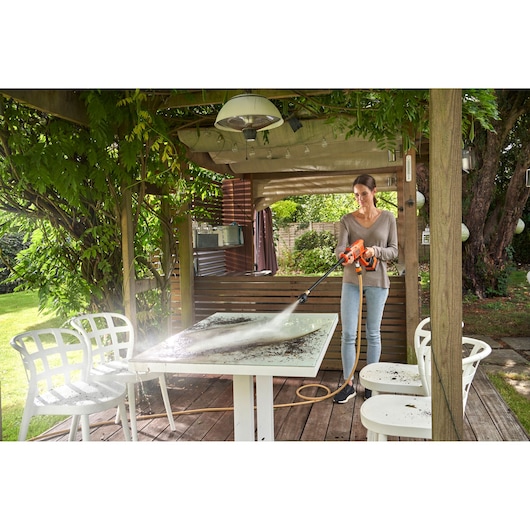 BLACKDECKER BZOQDW1 pressure washer cleaning patio table outdoors, person holding the tool.