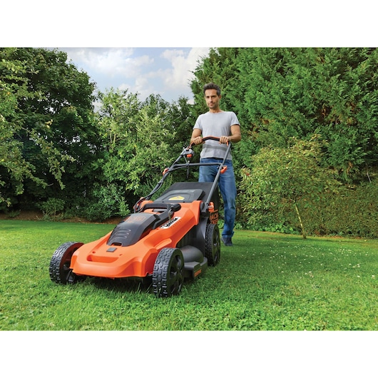 BLACKDECKER CLMA4820L2 lawn mower in use on grass by person outdoors, orange and black design.