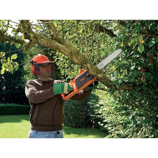 BLACKDECKER CS1840 chainsaw used outdoors for tree branch cutting, orange and black design, product in action.