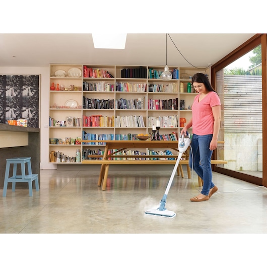 BLACKDECKER FSMH1300FX steam mop cleaning a modern living room floor with bookshelves in the background.