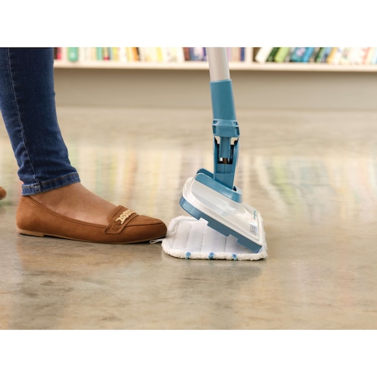 BLACKDECKER FSMH1300FX steam mop cleaning a smooth floor, close-up with shoe visible.