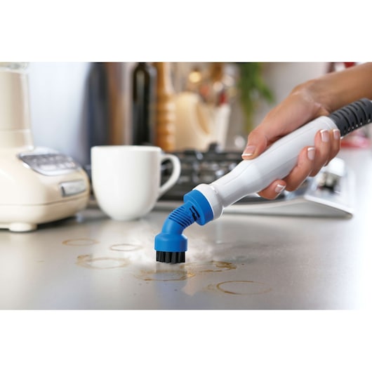 BLACKDECKER FSMH1300FX handheld steam cleaner with blue brush cleaning a kitchen countertop.
