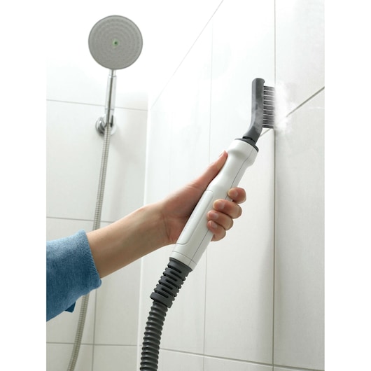 BLACKDECKER FSMH1300FX steam cleaner cleaning bathroom tile grout, handheld, white and grey, close-up angle.