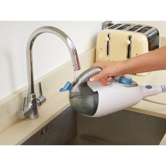 BLACKDECKER FSMH1300FX steam cleaner being filled with water at a kitchen sink, handheld side view.