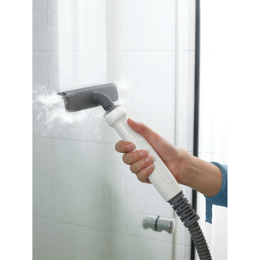 BLACK+DECKER FSMH1300FX steam cleaner cleaning a shower glass with handheld attachment, close-up.