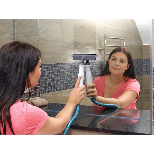 BLACKDECKER FSMH1300FX steam cleaner used to clean bathroom mirror, handheld type, blue hose, side angle.