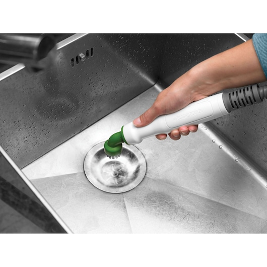 BLACKDECKER FSMH1321 handheld steam cleaner with green brush cleaning stainless steel sink.