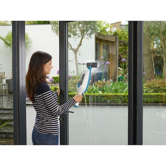 Photo of BLACKDECKER FSMH13E10 steam cleaner used on glass doors in a modern home interior.