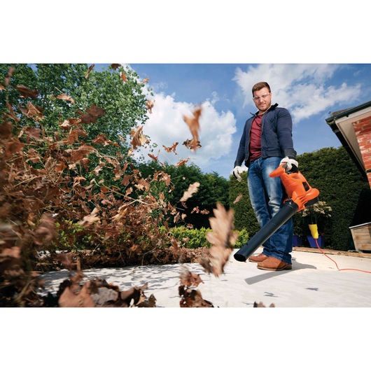 BLACKDECKER GW3030 leaf blower in use clearing dry leaves outdoors.