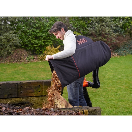 Photo of BLACKDECKER GWBP1 garden leaf collection bag emptying leaves next to wooden compost bin.