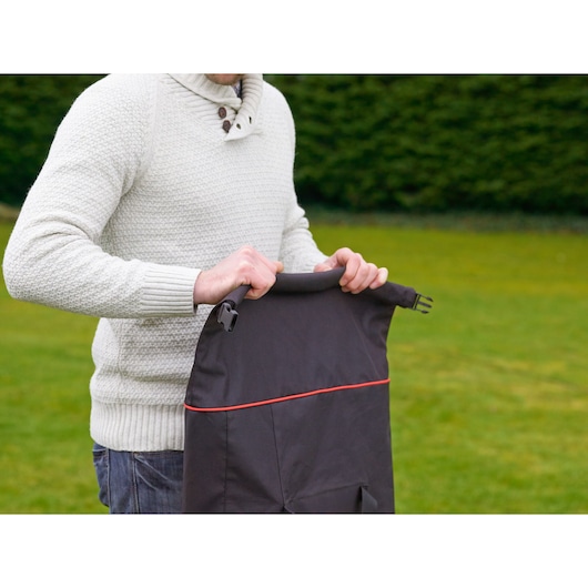 Photography of BLACKDECKER GWBP1 lawn bag with red trim held outdoors by person in light sweater.