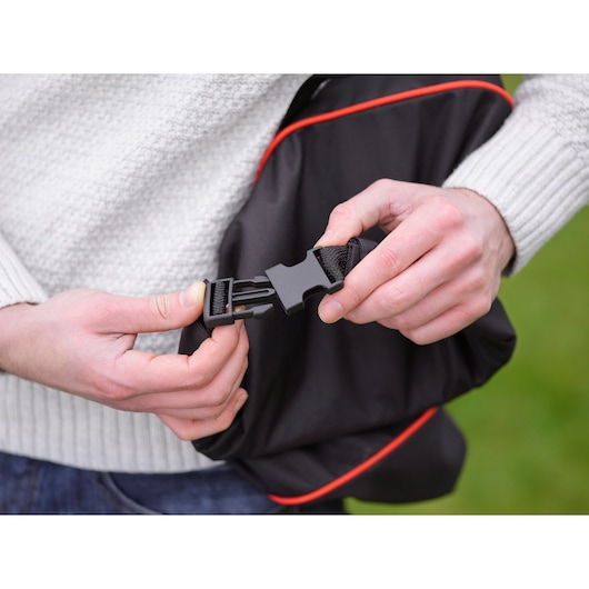BLACKDECKER GWBP1 photography of black bag buckle with red trim being fastened by hands.