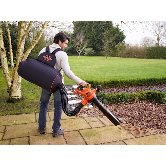 BLACKDECKER GWBP1 leaf blower and vacuum in use outdoors, person wearing backpack collection bag.