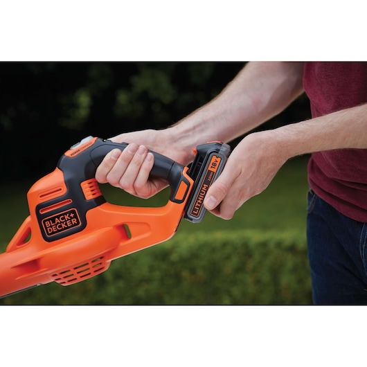 Photo of a BLACK+DECKER GWC1820PC cordless blower with 18V lithium battery being inserted, close-up view.