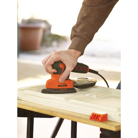 Photo of a BLACKDECKER KA2000 mouse detail sander being used on a wooden panel.