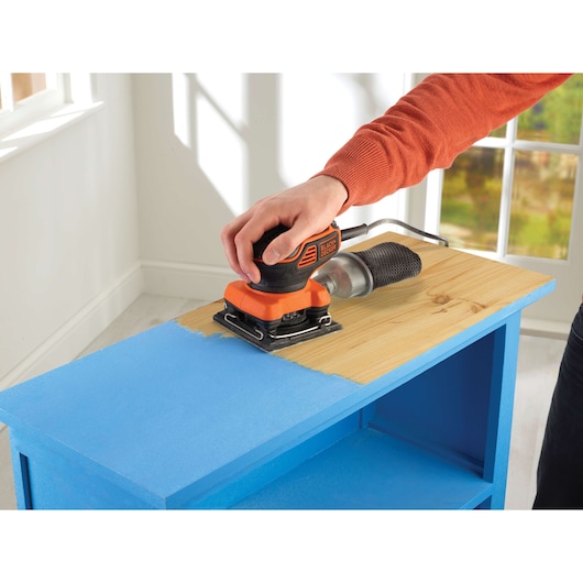 BLACKDECKER KA450 sander used on blue painted wood furniture, indoor setting.