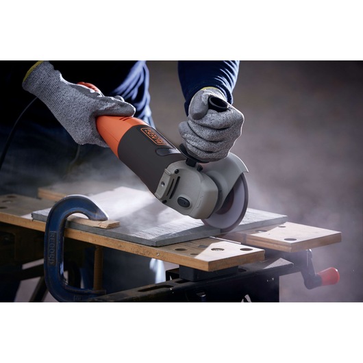 BLACKDECKER KG1202 angle grinder in use, cutting tile on workbench, gray and orange body.