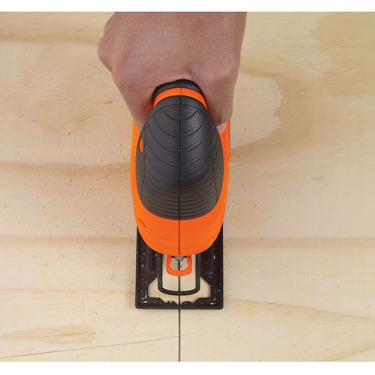 Top view of BLACKDECKER KS701EK jigsaw cutting along a marked line on light wood surface.