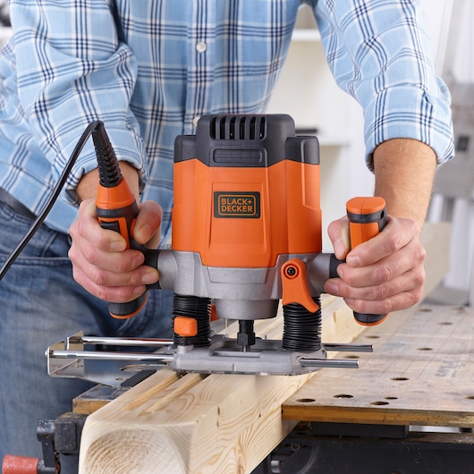 BLACKDECKER KW1200E woodworking router in use on a wooden plank, orange and black design.