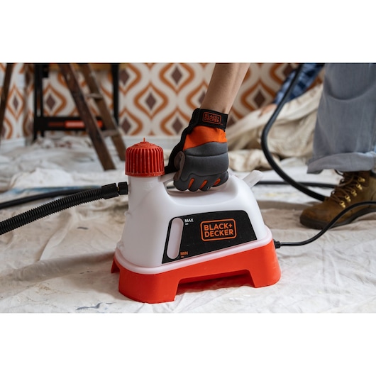 BLACK+DECKER KX3300T steam cleaner with red base in use, glove on handle, hose attached, indoor setting.