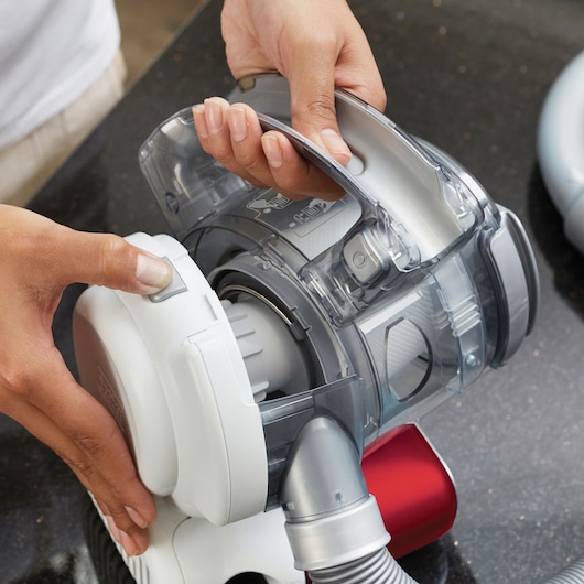 Close-up photo of BLACKDECKER PD1020L handheld vacuum cleaner with a person opening the dust container.