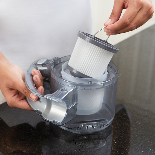 Photo of a person removing the filter from a BLACKDECKER PD1820L vacuum dust container.