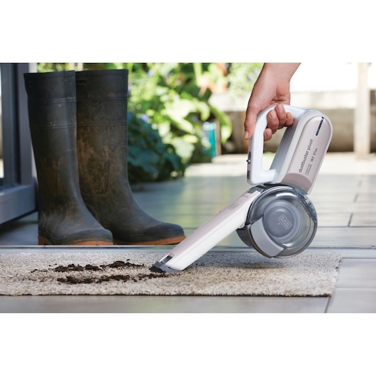 BLACK+DECKER PV1820LRGP handheld vacuum cleaning dirt from carpet, shown in use near muddy boots.