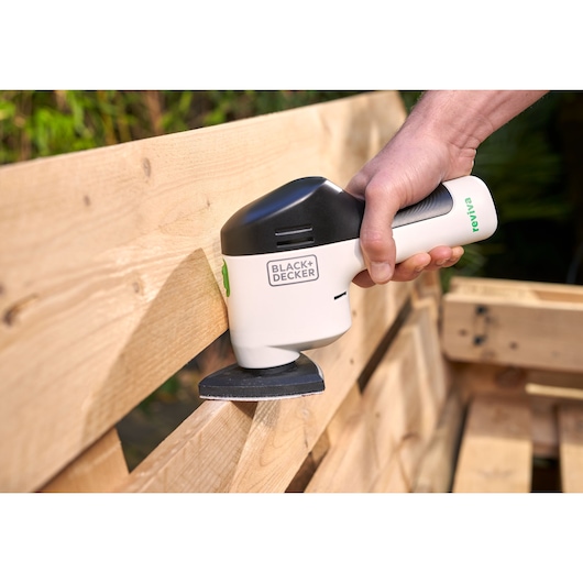 Photo of BLACK+DECKER REVDS12C handheld sander being used to sand a wooden pallet.