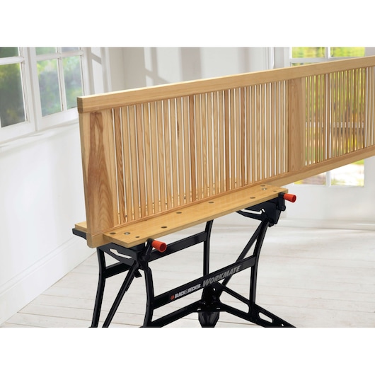 Photo of BLACK+DECKER WM626 workbench with wooden slatted panel clamped on top, indoor setting, side angle.